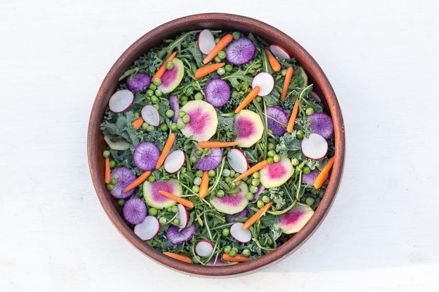 overhead image of vegan version of low FODMAP Greens Salad with Radishes & Peas in wooden salad bowl