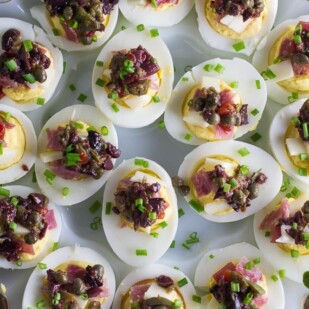 closeup overview of Low FODMAP Muffuletta Deviled Eggs on white egg plate