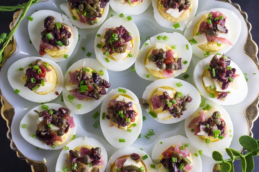 closeup overview of Low FODMAP Muffuletta Deviled Eggs on white egg plate