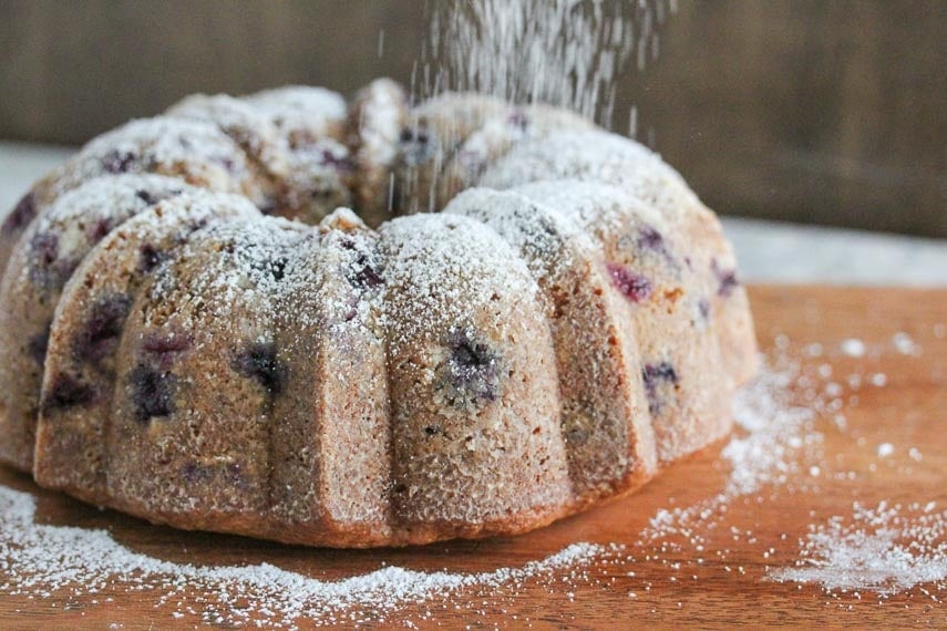 low FODMAP blueberry sour cream Bundt cake with confectioners' sugar showering over the top