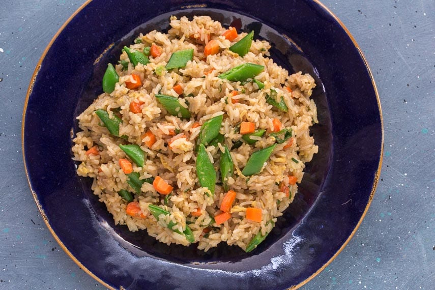 overhead image of low FODMAP fried rice with sugar snap peas and carrots on a blue plate