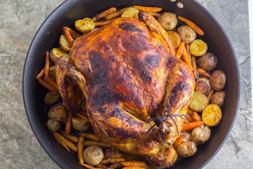 overhead image of whole roasted curry chicken with potatoes & carrots in roasting pan