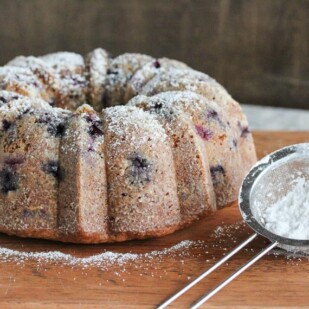 whole blueberry sour cream Bundt cake with confectioners' sugar alongside