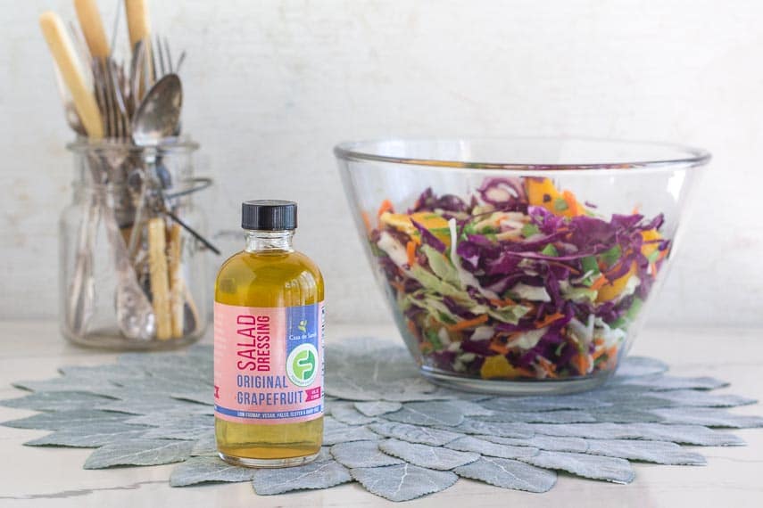 Low FODMAP Citrus Slaw with Creamy Grapefruit Dill Dressing in glass bow; bottle of Casa de Sante Original Grapefruit Salad Dressing in foreground