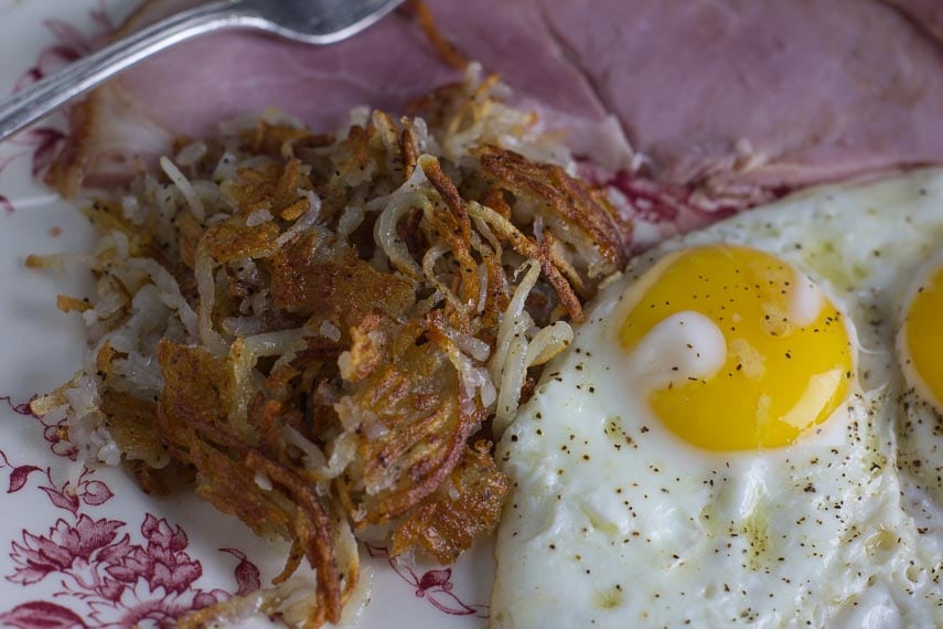 closeup of low fodmap hash browns with fried egg and ham on the side