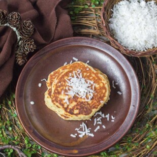 high overhead view of Low FODMAP Browned-Butter Coconut Pancakes on brown plate with brown cloth napkin on a rustic twig placemat