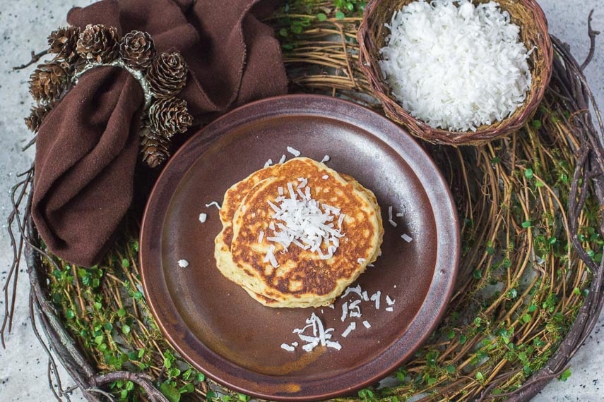 high overhead view of Low FODMAP Browned-Butter Coconut Pancakes on brown plate with brown cloth napkin on a rustic twig placemat