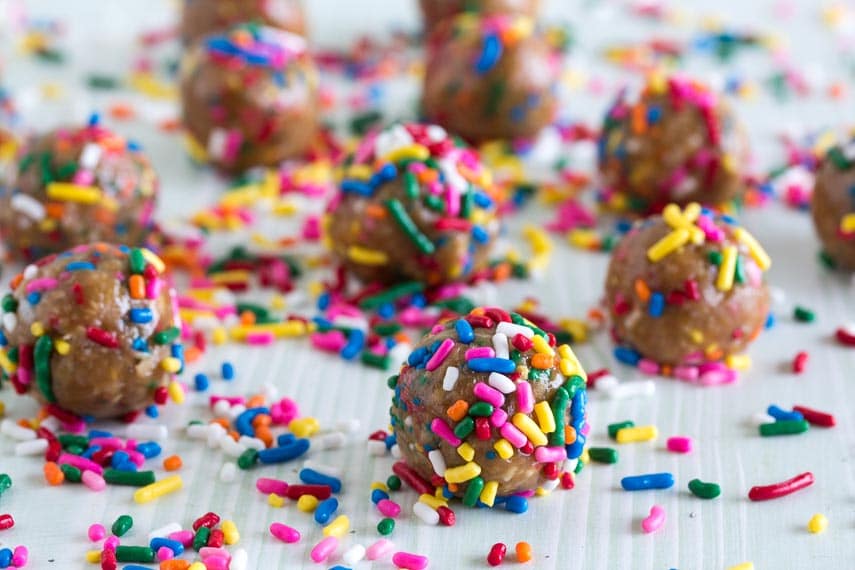 low FODMAP Birthday Cake Bliss Balls on pale surface with sprinkles all over