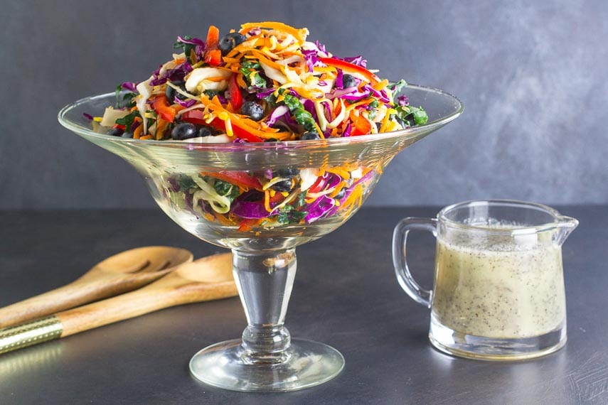 low FODMAP Eat the Rainbow Slaw in a footed glass bowl with poppy seed dressing alongside