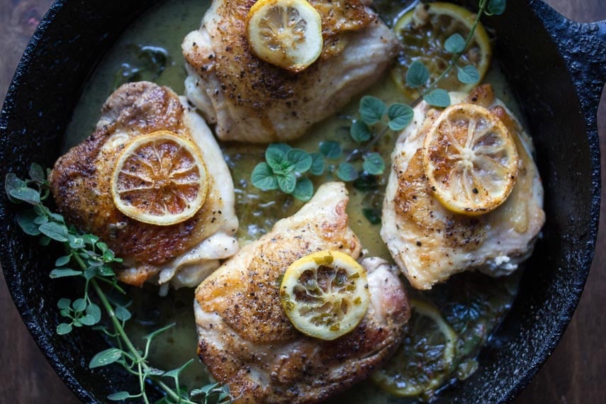 low FODMAP chicken thighs with lemon and fresh oregano in a cast-iron pan