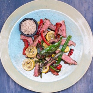 overhead view of Low FODMAP Grilled Rib Eye with Smoked Salt and Charred Vegetables on a blue and beige ceramic plate