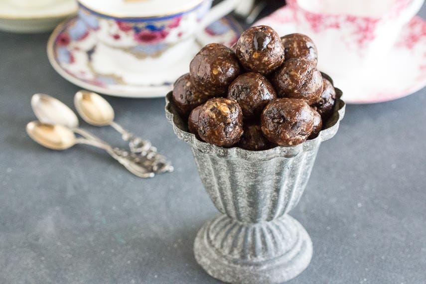Low FODMAP Mocha Espresso Power Balls in a grey aluminum footed dish; coffee cups and spoons in background