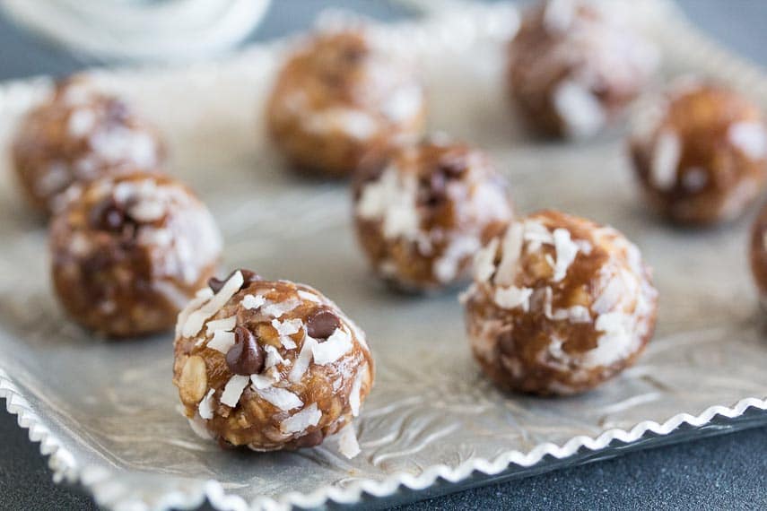 closeup of Low FODMAP Almond Joy Energy Bites on square aluminum platter against dark background