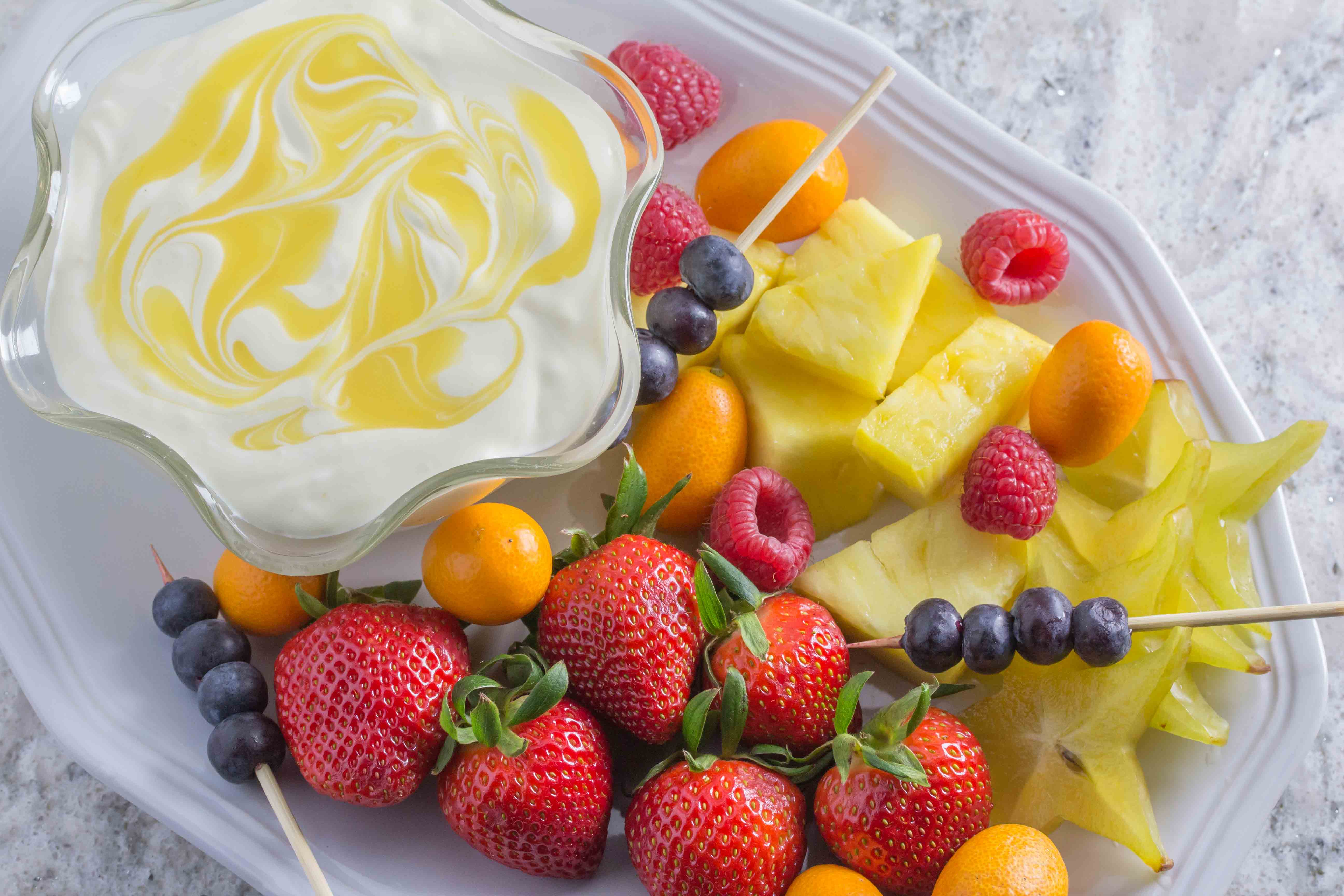 Low FODMAP Lime cheesecake dip in a decorative clear glass bowl; fruit alongside for dipping