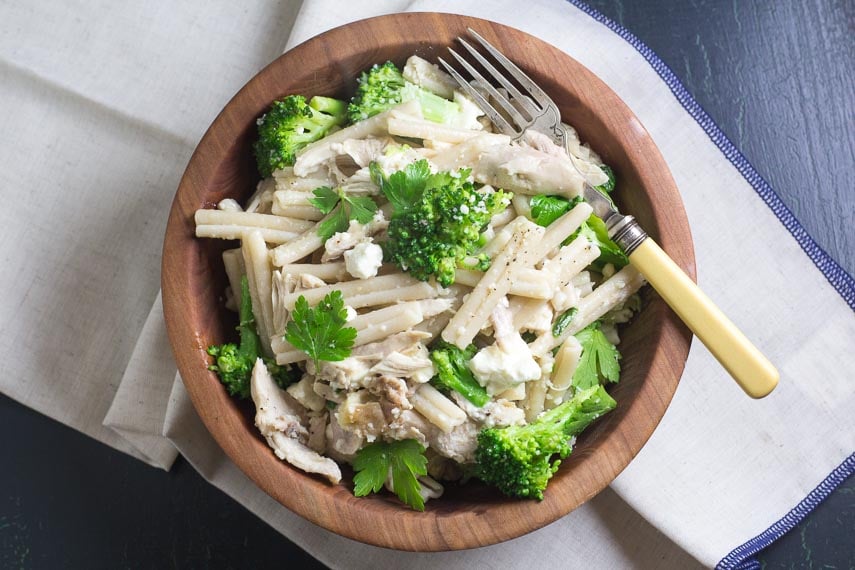 Low FODMAP Quick Pasta with Chicken, Broccoli & Goat Cheese in a wooden bowl with antique fork alongside
