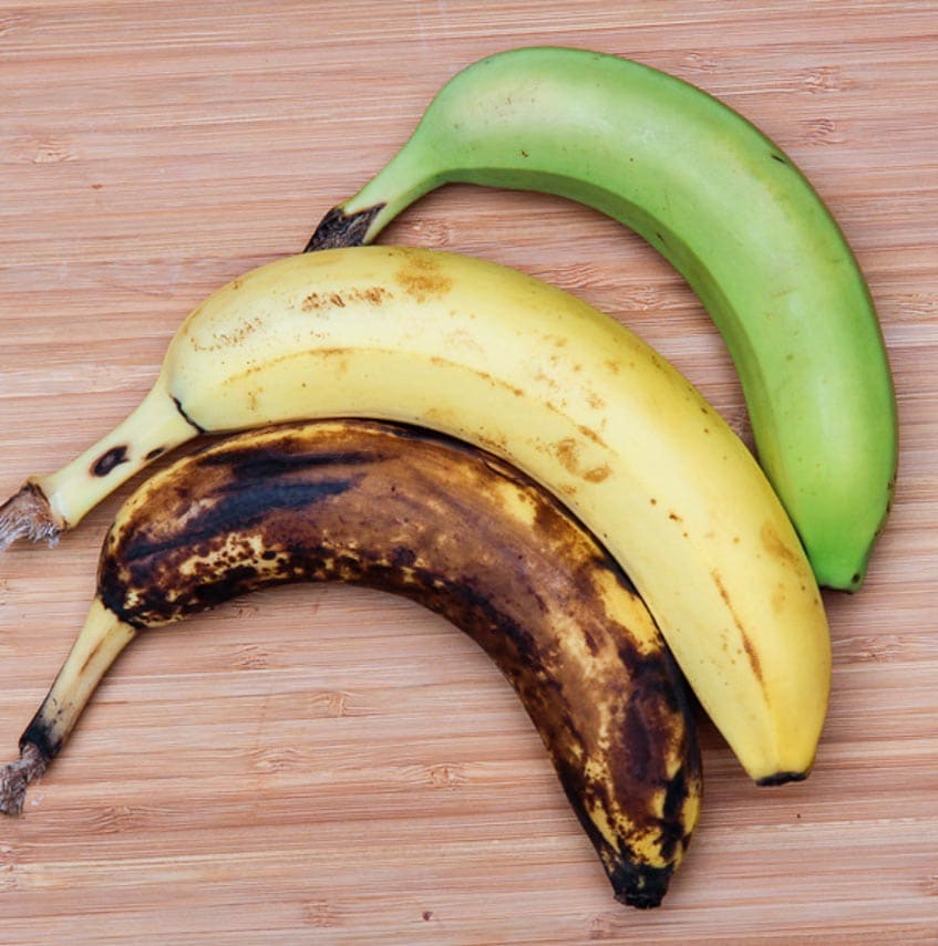 varying-degrees-of-ripeness-of-bananas; 3 bananas on a wooden board