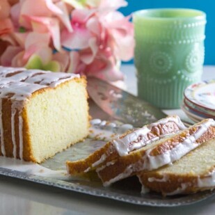 Glazed Low FODMAP Lemon Loaf on tin tray with plates in background