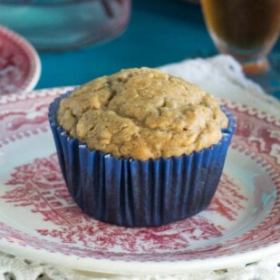 Low FODMAP High Protein Peanut Butter Muffins in a blue paper wrapper on a red and white antique plate