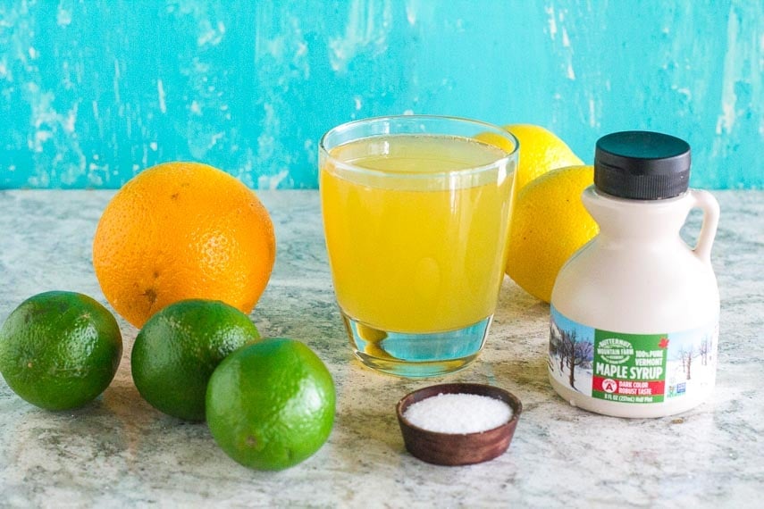Maple Lime Low FODMAP Sports Drink in a glass with ingredients. Aqua background