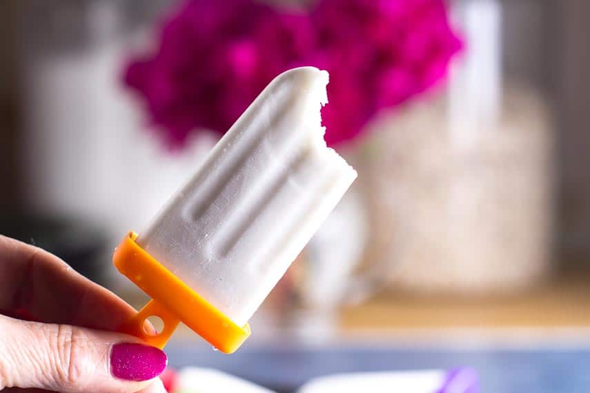 bite taken out of low FODMAP coconut popsicles held in manicured hand