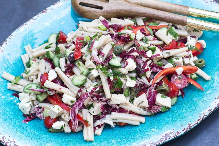 overhead Low FODMAP Mediterranean Pasta Salad on oval aqua platter with wooden serving spoons