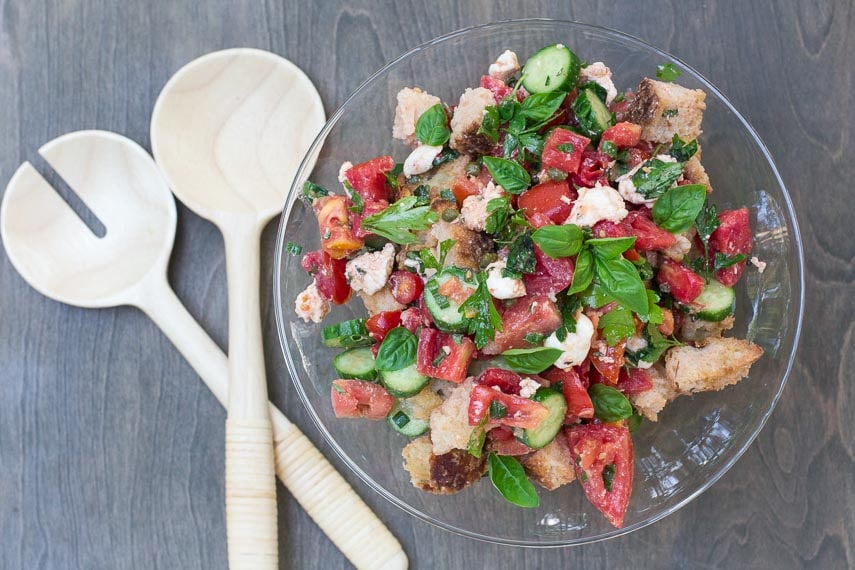 overhead Low FODMAP Panzanella with Tomatoes, Cucumbers & basil in a glass pedestal dish with wooden servers alongside-2