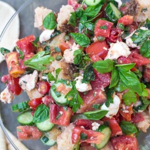 overhead Low FODMAP Panzanella with Tomatoes, Cucumbers & basil in a glass pedestal dish with wooden servers alongside