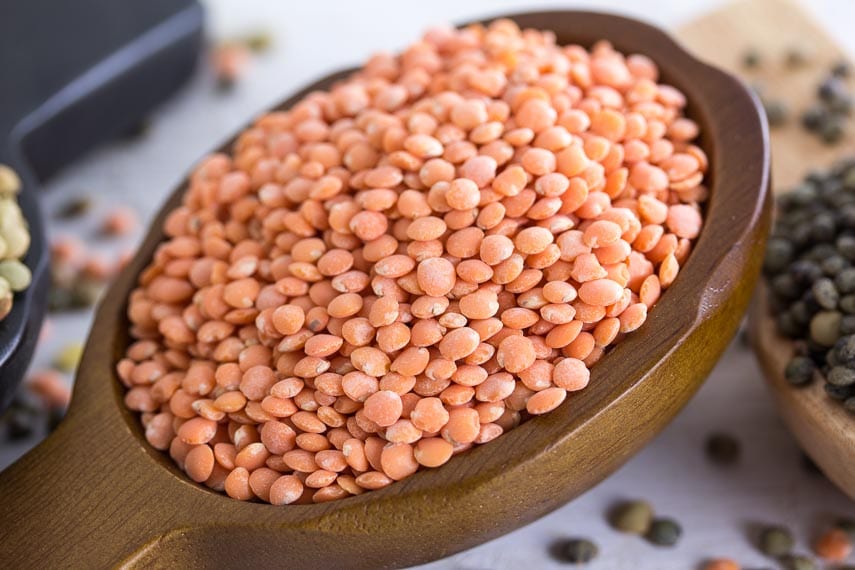 Dried Red lentils in a brown wooden scoop, closeup