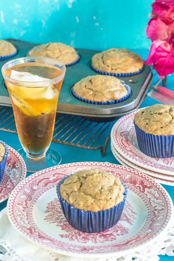 Low FODMAP High Protein Peanut Butter Muffins in a blue paper wrapper on a red and white antique plate with a glace of iced tea