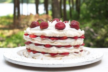 Low FODMAP Strawberry Coconut Meringue Cake on white wooden plate, outside on the deck