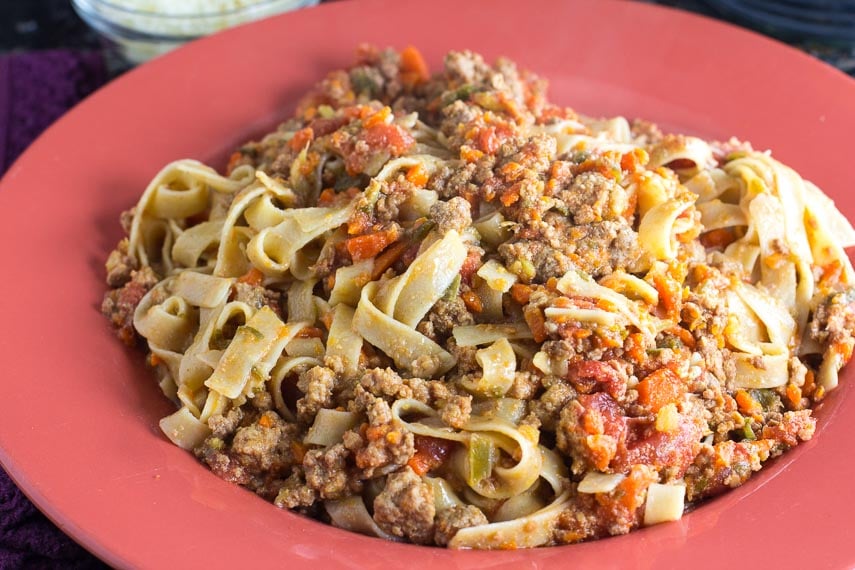 closeup of Low FODMAP Bolognese with lofo gf tagliatelle on a round orange shallow bowl