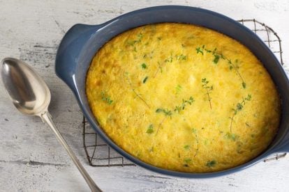 Low FODMAP corn puding on cooling rack; white wood surface and silver serving spoon