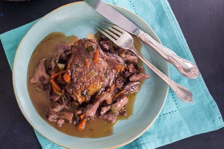 low FODMAP Coq au Vin on aqua plate with aqua napkin on blue background