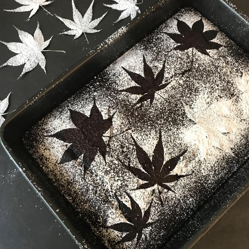 low FODMAP chocolate snack cake being stenciled with leaves and confectioners' sugar
