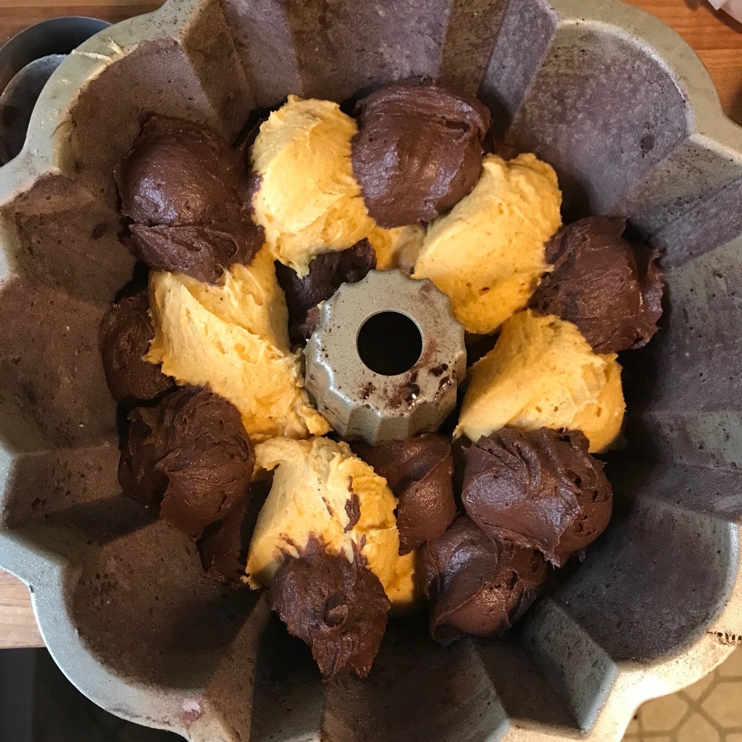 Pumpkin and cocoa batters being placed into Bundt pan