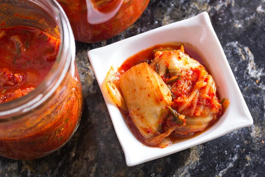 closeup of low FODMAP kimchi in small white dish on dark quartz counter