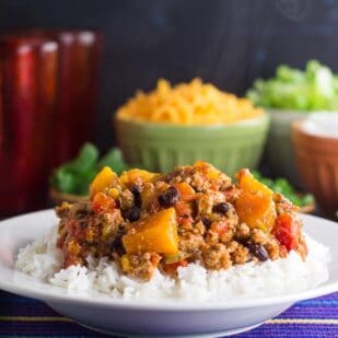 side view of Low FODMAP Turkey Chili with Winter Squash & Beans with rice in a white bowl