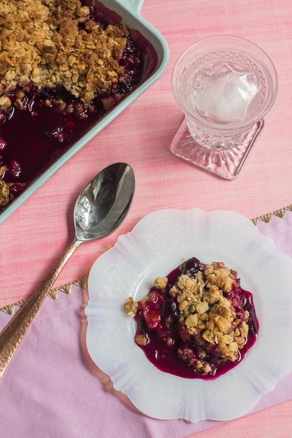 vertical image of Low FODMAP Cranberry Crisp with Grapes & Citrus on plate and in baking pan