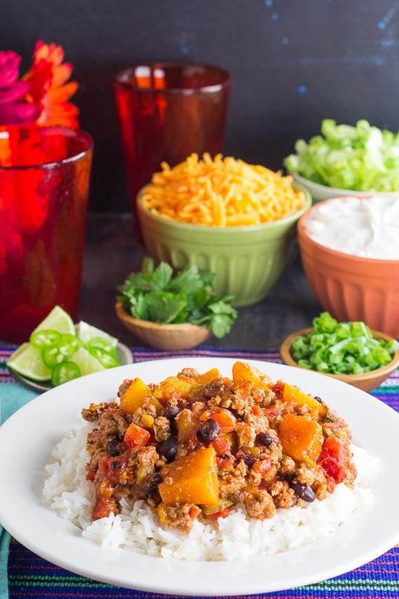 vertical image of Low FODMAP Turkey Chili with Winter Squash & Beans with rice in a white bowl