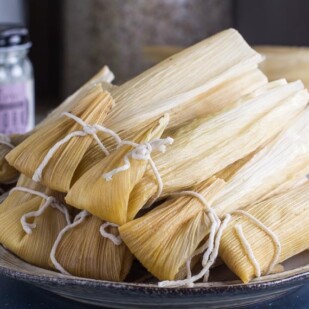 Low FODMAP tamales, piled on plate; jar of lard in background