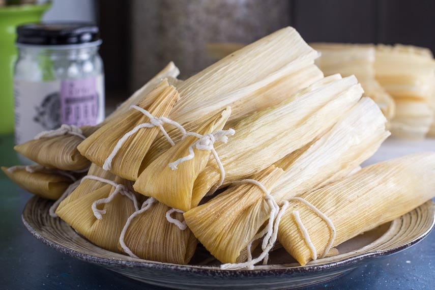 Low FODMAP tamales, piled on plate; jar of lard in background