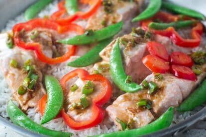 closeup of low FODMAP one-pot salmon with snow peas in skillet on gray quartz surface