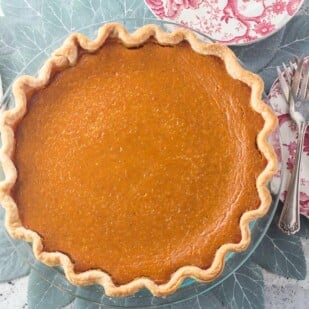 overhead image of low FODMAP classic pumpkin pie in glass pie plate with silver server