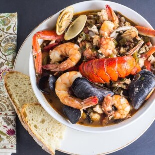 overhead of Low FODMAP Cioppino in white bowl with sourdough bread