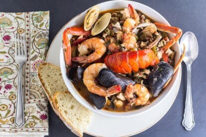 overhead of Low FODMAP Cioppino in white bowl with sourdough bread