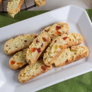 Low FODMAP Tropical Biscotti on white platter with green napkin; cooling on cooling rack in background