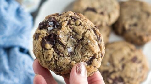 closeup of low FODMAP vegan chocolate chunk cookie sprinkled with salt; held in hand