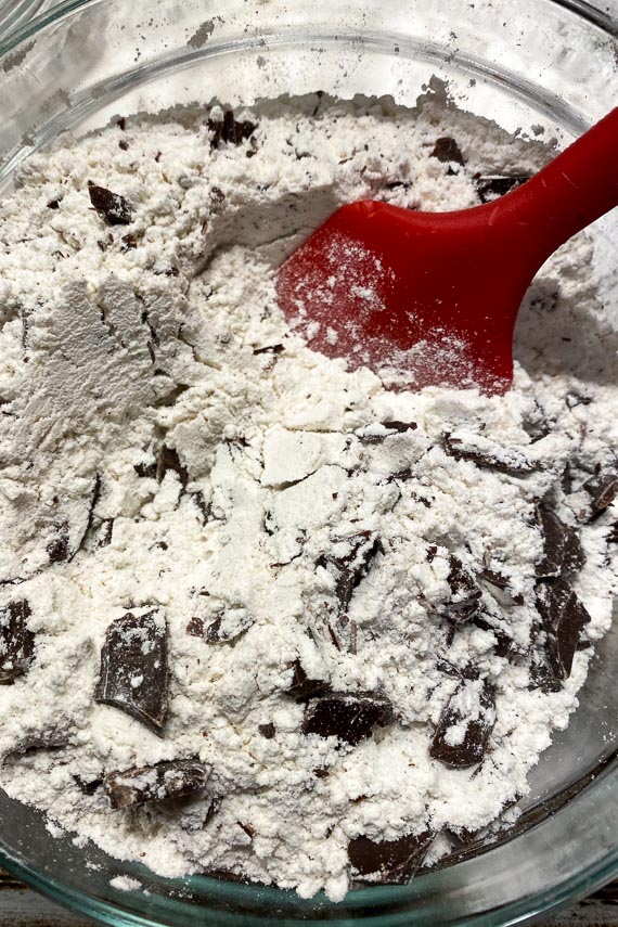 dry ingredients tossed together for low FODMAP vegan chocolate chunk cookies in bowl with red spatula