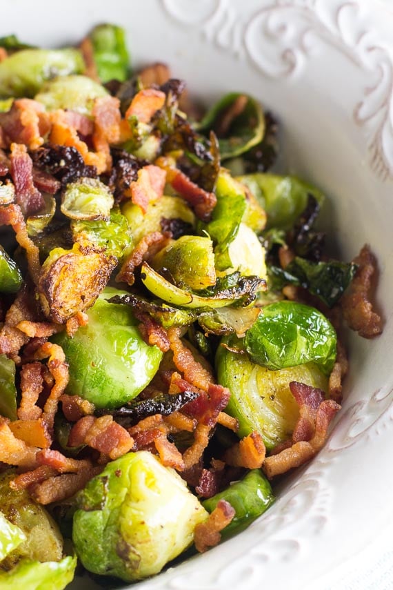 vertical image of low FODMAP Brussels sprouts and bacon in white dish with raised decorative edge