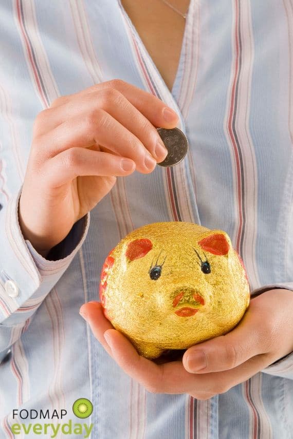 Picture of a woman holding a piggy bank and placing a coin in it. 